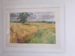 Landscape of wheat fields in watercolour framed by world under glass